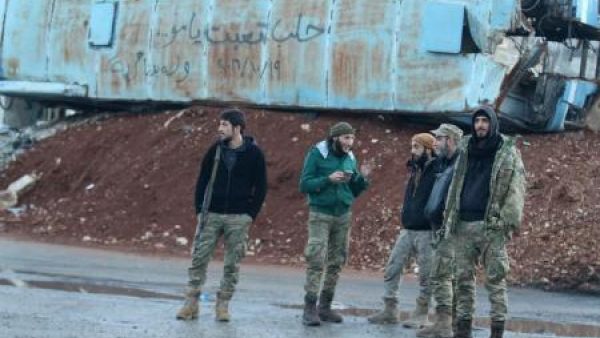 مقاتلون من المعارضة السورية يقفون بجوار حافلة مدمرة في حي باب الحديد

