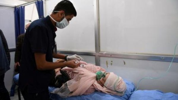 امرأة تحصل على مساعدة طبية في مستشفى في حلب بعد هجوم بالغاز يوم السبت
