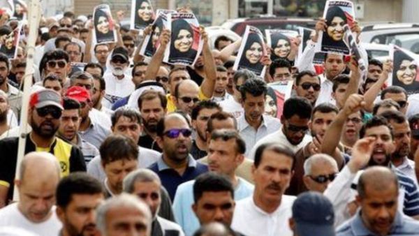 مشيعون يحملون صور المرلأة التي قتلت في حادث يوم الجمعة في المنامة عاصمة البحرين في جنازتها بقرية السترة يوم السبت
