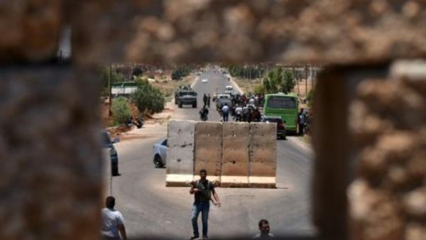 حافلة تنقل نازحين سوريين تقف على حاجز في بلدة بصرى في جنوب سوريا
