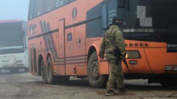 مقاتل من المعارضة يقف بجوار حافلة تقل سكانا من بلدتي الفوعة وكفريا بموجب اتفاق مع النظام في إدلب يوم الجمعة

