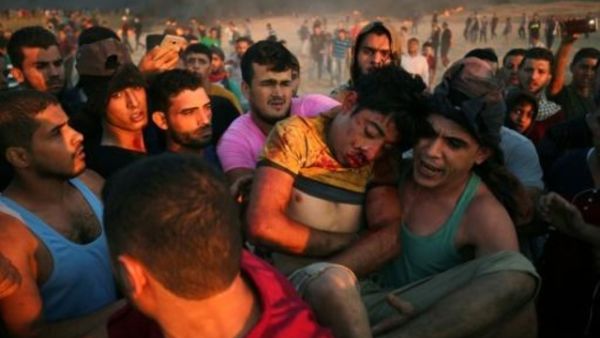 فلسطينيون يحملون فتى أصيب بجروح خلال مواجهات على السياج الفاصل بين إسرائيل وقطاع غزة
