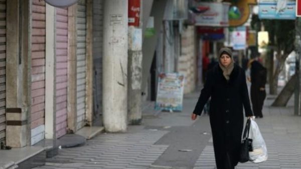 فلسطينية وسط محلات تجارية مغلقة بسبب الاضراب في غزة
