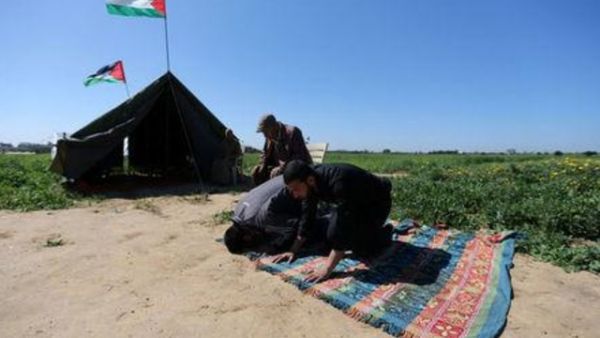 فلسطينيون يؤدون الصلاة بجوار خيمة بالقرب من الحدود مع اسرائيل
