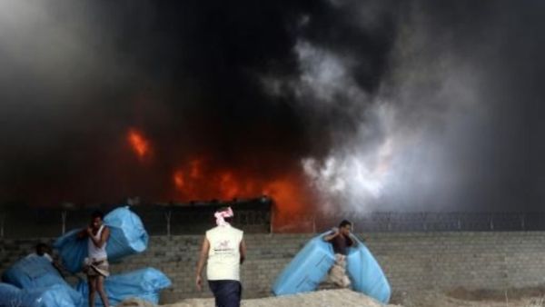 عمال إغاثة يحاولون انقاذ مساعدات غذائية من الحريق الذي اندلع في مخازن تابعة لبرنامج الأغذية العالمي في مدينة الحديدة الساحلية على البحر الأحمر
