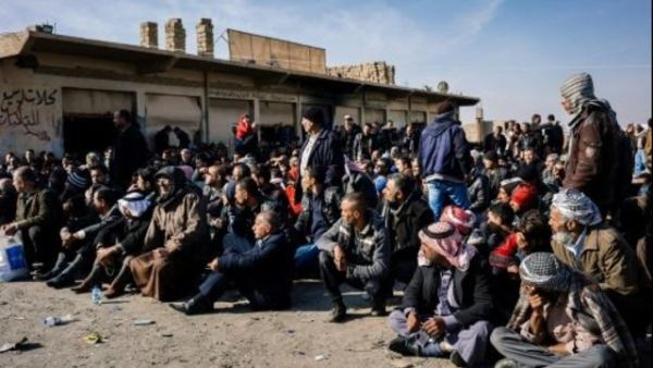 رجال نزحوا من المعارك في الموصل في انتظار التحقق من هوياتهم قرب بلدة برطلة

