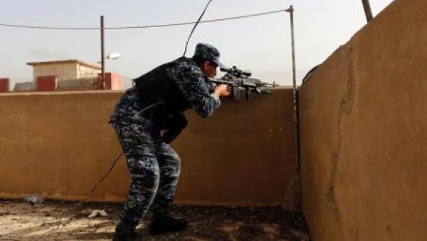 شرطي عراقي يصوب بندقيته على مواقع لمقاتلي تنظيم الدولة الإسلامية خلال اشتباكات في غرب الموصل
