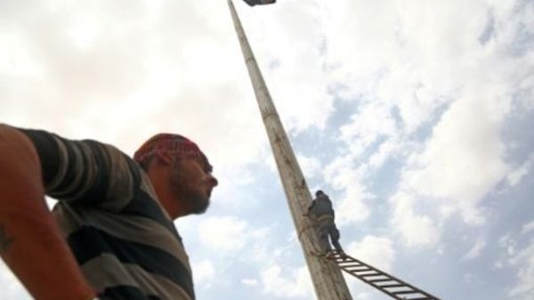 عنصر من قوات سوريا الديموقراطية ينزل راية لتنظيم الدولة الاسلامية في بلدة الطبقة
