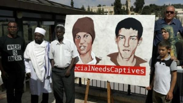 أقارب هشام السيد وأفيرا منغيستو أمام لافته تحمل صورتيهما في القدس
