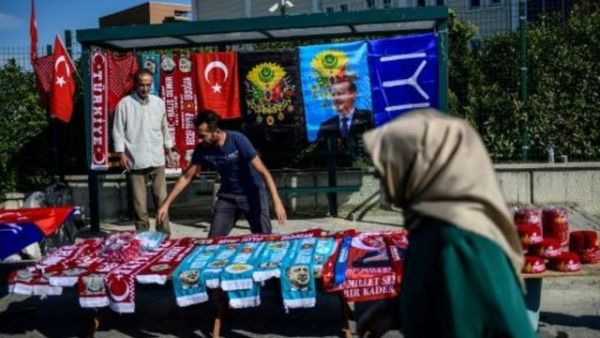 امرأة تسير أمام بسطة لبيع شالات تحمل صور الرئيس رجب طيب اردوغان قرب محكمة سجن سليفري في اسطنبول
