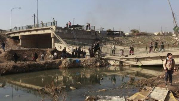 مشردون يعبرون جسرا في ضاحية المثنى بالموصل
