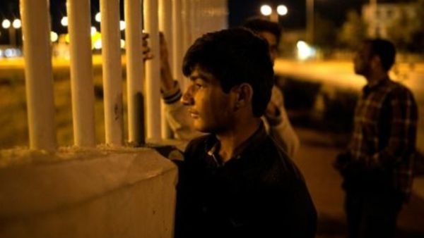 مهاجر افغاني ينظر الى عبارة عبر السياج في مرفأ باتراس (غرب اليونان)

