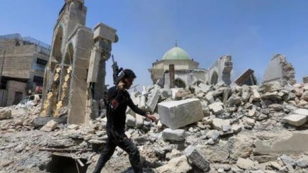 أحد أفراد قوة مكافحة الإرهاب في العراق يمشي بجوار أنقاض مسجد النوري الكبير في الحي القديم بمدينة الموصل في شمال العراق يوم الجمعة
