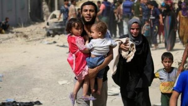 نازح عراقي فر من اشتباكات يحمل طفلين في غرب الموصل يوم السبت
