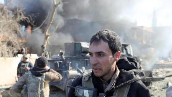 أحد أفراد القوات الخاصة العراقية يمشي أمام سيارة همفي بعد تفجير انتحاري نفذه أحد مقاتلي تنظيم الدولة الإسلامية في الموصل
