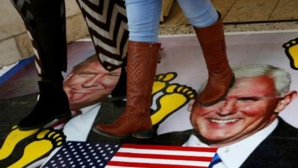 فلسطينيون يدوسون على ملصق عليه صورتي ترامب وبنس، خلال تظاهرة في جامعة القدس المفتوحة في قرية دورا قرب الخليل
