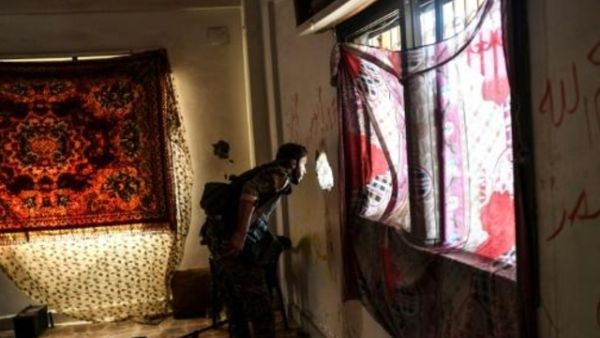 احد عناصر قوات سوريا الديموقراطية يتفقد منزلا في منطقة تمت استعادتها مؤخرا من تنظيم الدولة الاسلامية في وسط الرقة

