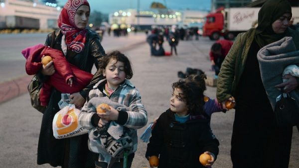 Migrant mothers with her children received oranges upon their arrival to the port of Piraeus in Athens area along with other migrants from the Greek Islands of Lesbos and Chios on February 18, 2016. (AFP/Louisa Gouliamaki)