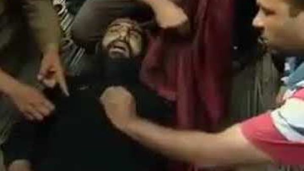 اشخاص يتجمهرون حول جثة القس سمعان بعيد مقتله

