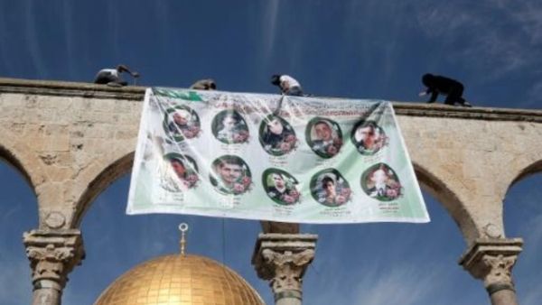 فلسطينيون يعلقون لافتة عليها صور شهداء تحتجز اسرائيل جثامينهم
