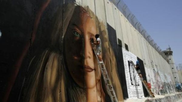 لوحة جدارية عملاقة للفلسطينية عهد التميمي قرب بيت لحم رسمها الفنان الايطالي جوريت اوغوتش 
