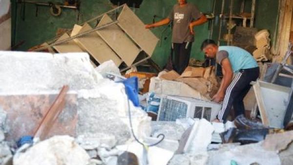 رجلان يقفان بين حطام ناتج عن غارة جوية على مستشفى في غربي إدلب
