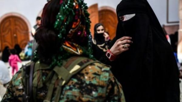 امرأة سورية تتحدث مع مقاتلة من قوات سوريا الديموقراطية فيما يتجمع المدنيون على الجانب الغربي اثر فرارهم من وسط الرقة

