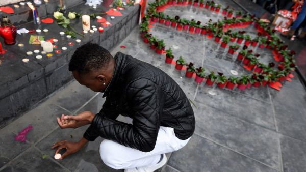 A man puts a candle near a peace symbol made with flowers on place de la Republique in Paris on November 13, 2016 as France marked the first anniversary of the Paris attacks for the relatives of the 130 people killed. (AFP/Alain Jocard)