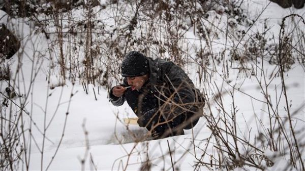 A refugee eats his meal while sitting in the snow in Belgrade on January 11, 2017, as temperatures drop to -15 degrees Celsius. (AFP/File) 