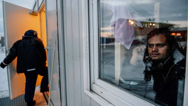 A refugee looks through a window at the arrival centre for refugees near the town on Kirkenes in northern Norway on Nov. 11, 2015. (AFP/Jonathan Nackstrand)