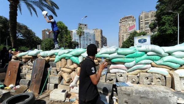 EGYPT, Cairo : A supporter of the Muslim Brotherhood and Egypt's ousted president Mohamed Morsi stands on top of a make-shift barricade as they demonstrate near Cairo university on July 26, 2013. (AFP PHOTO/FAYEZ NURELDINE) 