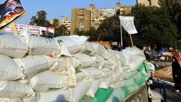 EGYPT, Cairo : A supporter of Egypt's deposed president Mohamed Morsi (portrait-L) walks past a barricade in Cairo on July 31, 2013. AFP PHOTO / FAYEZ NURELDINE