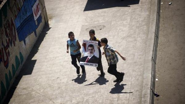 Egyptian children run while holding a portrait of ousted president Mohamed Morsi during a demonstration in support of Morsi in Cairo, on August 9, 2013. AFP PHOTO/GIANLUIGI GUERCIA