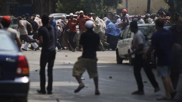 EGYPT, Cairo : Local residents (front) throw stones towards supporters of ousted president Mohamed Morsi during clashes in downtown Cairo on August 13, 2013.  AFP PHOTO/GIANLUIGI GUERCIA