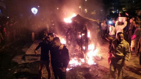 Angry Egyptians set fire to a microbus, said to be belong to a company owned by a businessman who supports the Muslim Brotherhood, after passengers allegedly held up four fingers, the symbol known as "Rabaa", during the funeral of those killed in a car bomb attack earlier in the day, in the Egyptian city of Mansoura, North of Cairo, on December 24, 2013. [AFP]