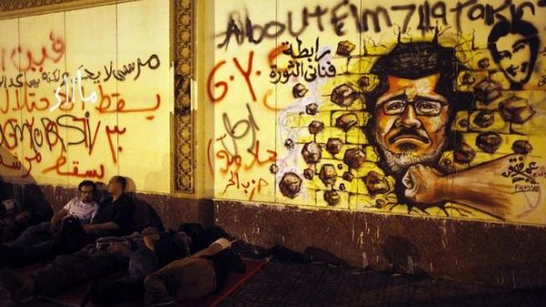 Egyptian opposition demonstrators calling for the ouster of President Mohamed Morsi sleep next to a wall covered in anti-Morsi graffiti (Mahmud Khaled / AFP)