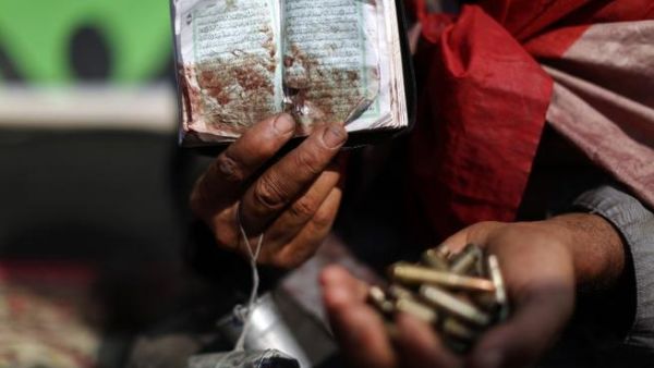 An Egyptian supporter of deposed president Mohamed Morsi holds a copy of the Koran stained with blood and empty casing as he attends a rally in support of the former Islamist leader (AFP)