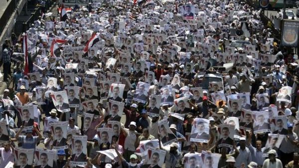Supporters of the Muslim Brotherhood and Egypt's ousted president Mohamed Morsi carry his portrait as they demonstrate outside Rabaa al-Adawiya mosque on July 26, 2013. AFP PHOTO/MOHAMED EL-SHAHED