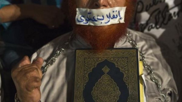 EGYPT, Cairo : An Egyptian man holds a copy of Quran and puts tape on his mouth with Arabic slogan "Military coup" during an open sit in outside Rabaa al-Adawiya mosque in Cairo on August 1, 2013. AFP PHOTO / KHALED DESOUKI