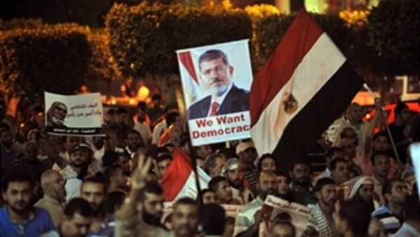 Egyptian supporters of the deposed president Mohamed Morsi hold his portrait and wave the national flags during a demonstration against the government in Cairo on July 31, 2013 ( FAYEZ NURELDINE/AFP/Getty Images)