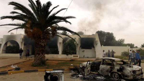 Libyan men stand outside a building used by Ansar al-Sharia militia after it was torched by residents on November 25, 2013 in Benghazi. [Abdullah Doma/AFP]