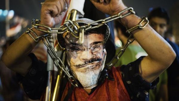 EGYPT, Cairo : A chained protester wearing a picture of President Morsi poses as hundreds of Egyptian anti-government protesters shout political slogans against Egyptian President Mohammed Morsi in Egypt's landmark Tahrir square as they watch Morsi's speech protesting against government and the Muslim Brotherhood on June 26. (AFP)