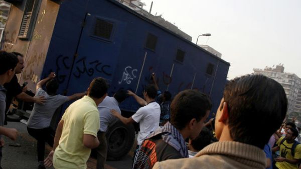 Supporters of Egyptian ousted president Mohamed Morsi attack a police vehicle in Cairo's eastern Nasr City district on October 11, 2013, after clashes broke out during a demonstration against the military. (Image credit: AFP)