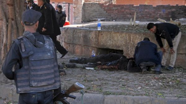 Egyptian security forces check a body at the site of a bomb attack next to a police checkpoint in the western Talibiya district of the capital Cairo on December 9, 2016. (AFP/Stringer)