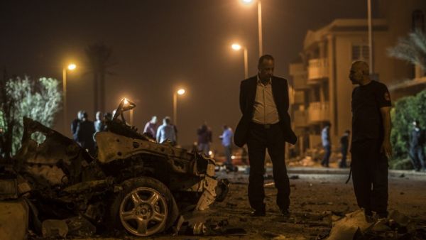 Egyptian officials inspect the wreckage of a car bomb that exploded in a Cairo suburb after Egypt's deputy prosecutor general drove by late on September 29, 2016, wounding a passerby. (AFP/Khaled Desouki)