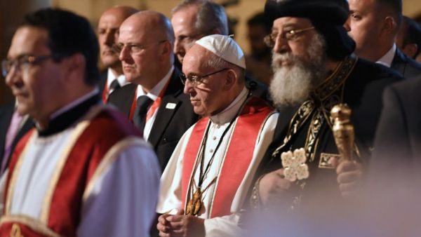 Pope Francis (C) stands near to Coptic Pope Tawadros II (R) as he prepares to light a candle during a visit at the Saint Peter and Saint Paul church in Cairo, which was target by a suicide bomb attack that killed 29 people last December, on April 28, 2017. (AFP/Andreas Solaro)