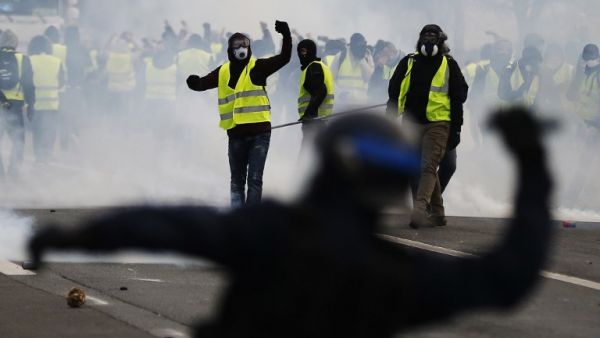 Protestors wearing a yellow vest (gilet jaune), clash with French riot police during a demonstration against rising costs of living they blame on high taxes in Mondeville near Caen. (AFP)