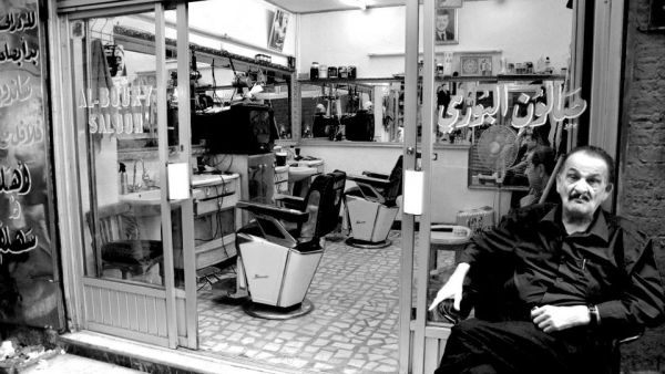 A man sits outside of his barber shop in Amman, Jordan.  Many older residents of the city's historic neighborhoods feel that the up-and-coming hipster scene is pushing them away.  (Albawaba/Madeline Edwards)