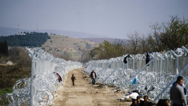 Refugees walk alongside a barbed-wire fence on the Greek-Macedonian border near Gevgelija, on March 1, 2016. (AFP/Dimitar Dilkoff)