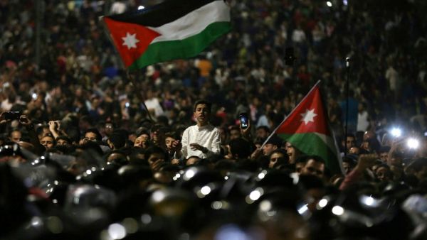 Protesters wave flags near Jordanian security forces during a demonstration outside the prime minister's office in the capital Amman late on June 3, 2018. Khalil Mazraawi /AFP File Photo) 